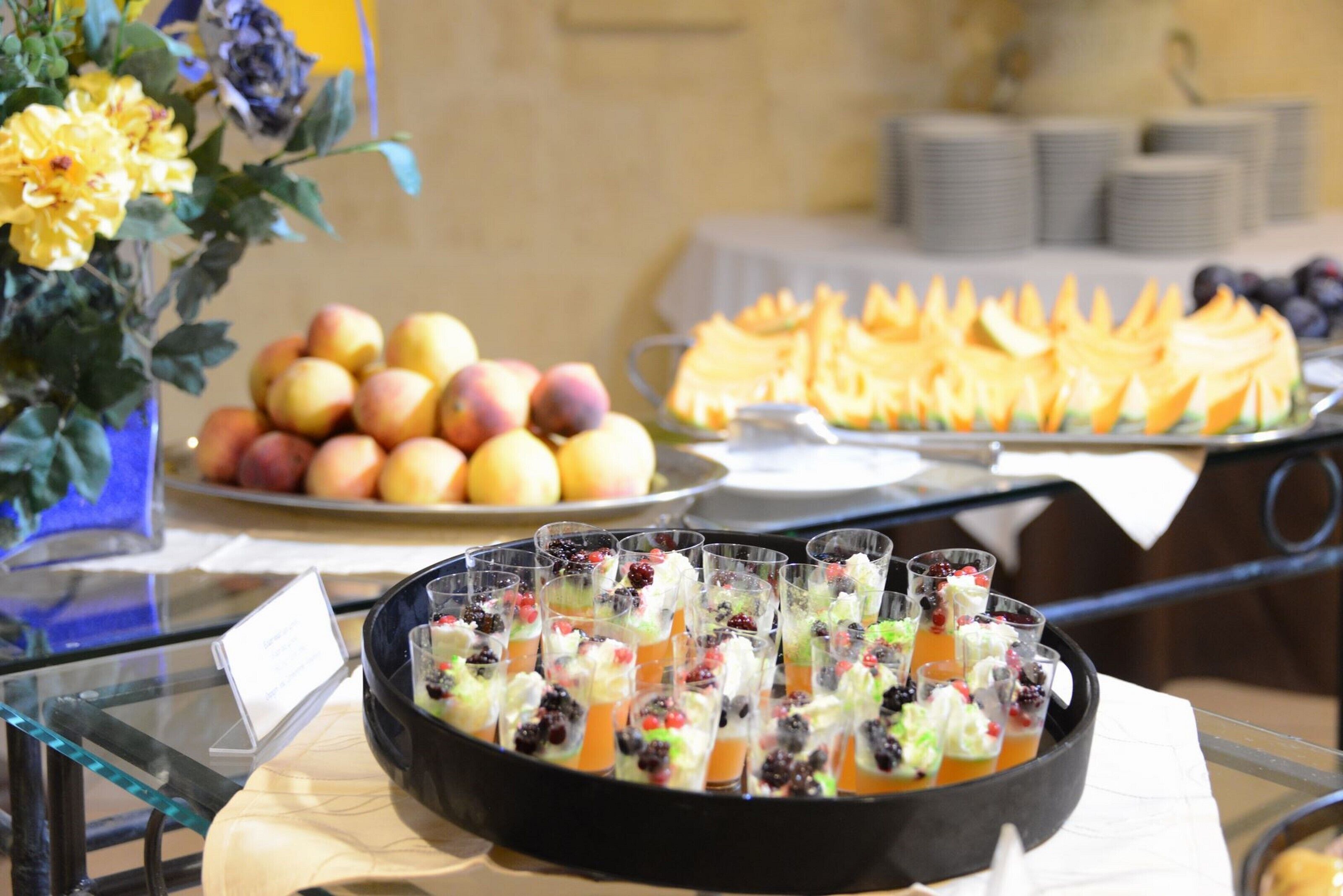 Ein Buffet mit verschiedenen Speisen, darunter Obst, Gebäck und Obstbechern.