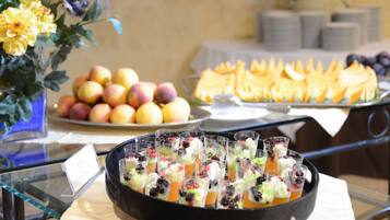 Ein Buffet mit verschiedenen Speisen, darunter Obst, Gebäck und Obstbechern.