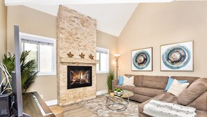 A living room with a fireplace, a sofa, a coffee table, and artwork on the wall. - 1 House from the Sand w/ Rooftop Deck on 28th Street (Newport Beach)