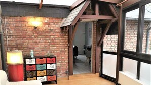 A cozy room with a white sofa, a wooden coffee table, and a brick wall with a loft area. - Le Greyhound - Grand Appartement Centre-ville (Soissons)