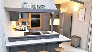 A compact kitchen with a bar area, a microwave, a stove, and a sink. - Le Greyhound - Grand Appartement Centre-ville (Soissons)