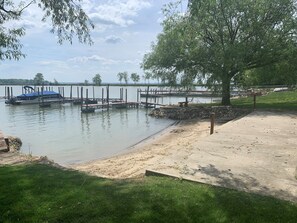 Une jetée au bord du lac, avec un bateau, une zone herbeuse et un mur de pierres.