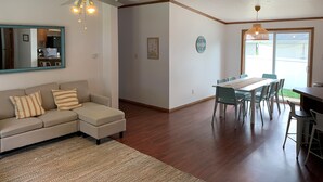 Ein Wohnzimmer mit einer Couch, einem Esstisch mit Stühlen, einem Deckenventilator und einem großen Spiegel.