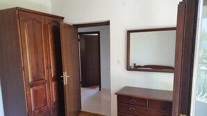 Una habitación con un armario de madera, un aparador con cajones y un espejo en la pared.