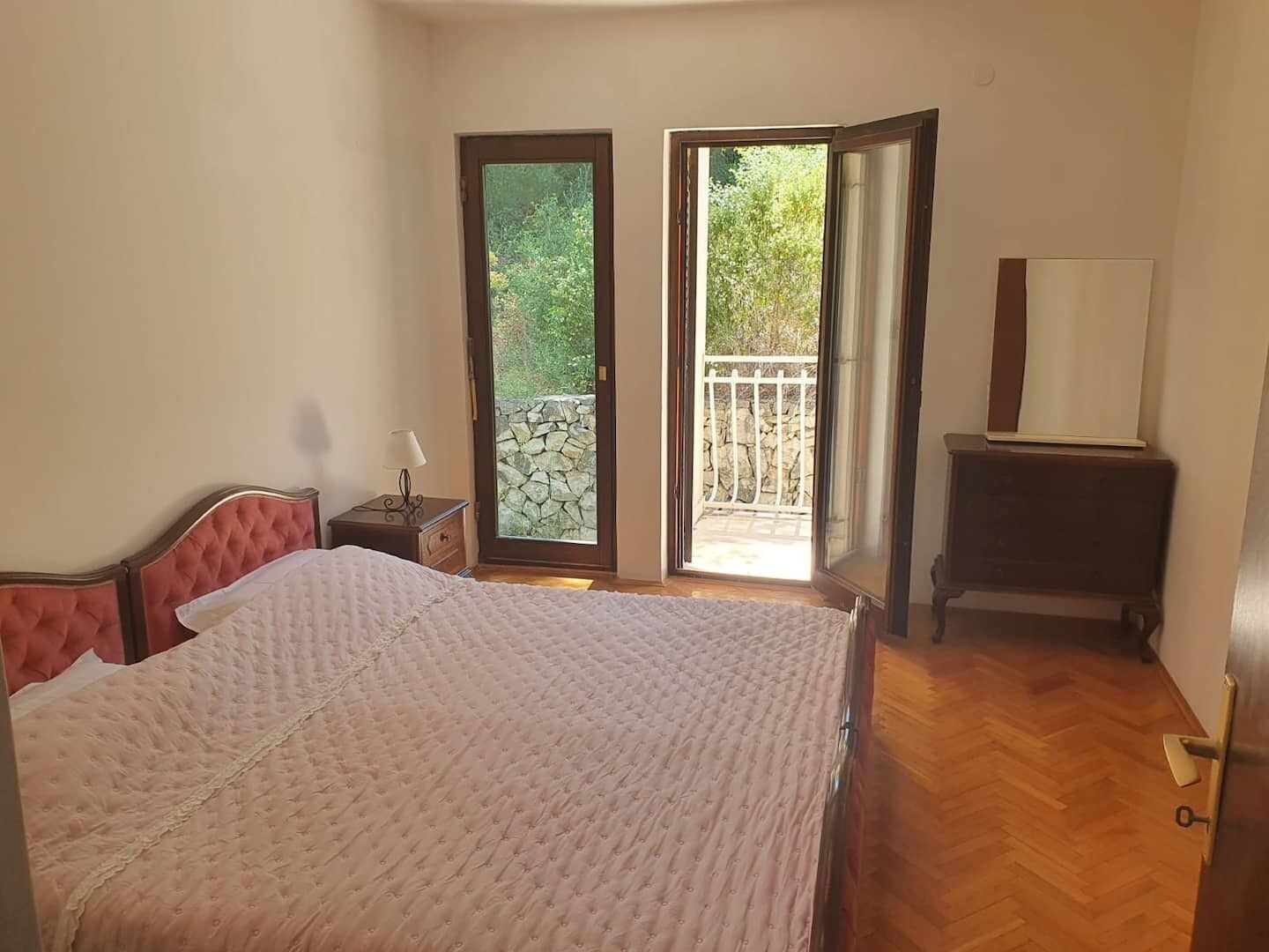Et soveværelse med en seng, et natbord, en kommode og en dør til en balkon.