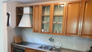 Una cocina con armarios de madera, un lavamanos de acero inoxidable y un horno empotrado.
