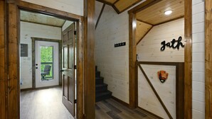 Un intérieur en bois avec un escalier, une porte donnant sur un balcon et un mur orné d’un écusson.