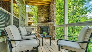 Une terrasse extérieure couverte, avec des murs en pierre, une cheminée et du mobilier d’extérieur.