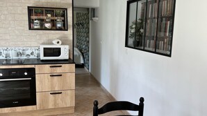A modern kitchen with a Bosch oven, wooden cabinets, a microwave, and a dining area with a table and chairs.
