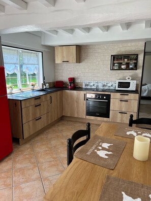 A kitchen with wooden cabinets, a red coffee maker, a microwave, and a dining table with placemats.