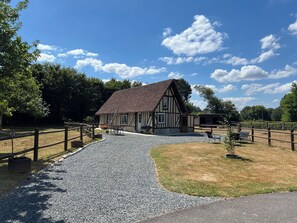 A traditional half-timbered building with a gravel driveway leading to a wooden fence.