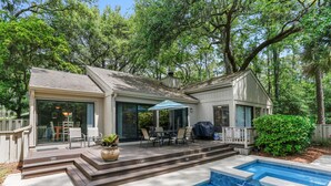 A house with a patio, a pool, and a covered outdoor dining area.