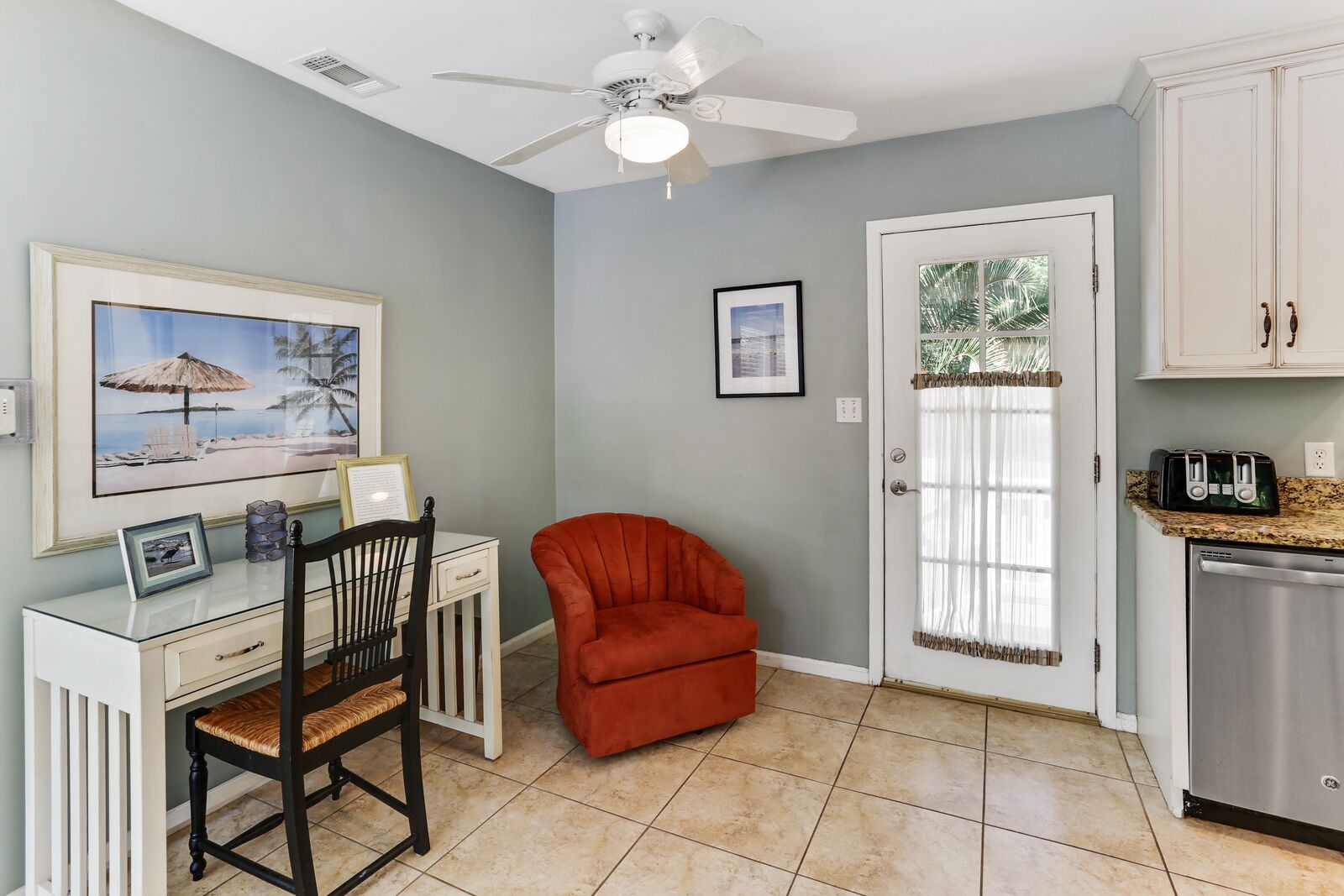 A compact kitchen with a dining area, a ceiling fan, and a door with a window.