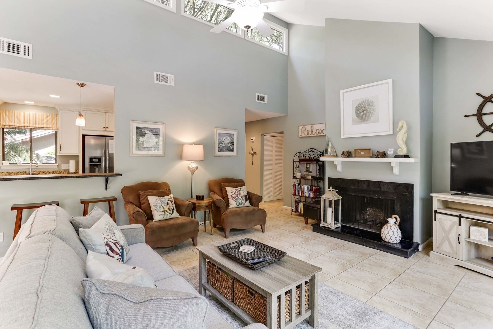 A spacious living room with a high ceiling, a fireplace, a television, and a bookshelf.