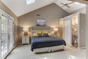 Relax in this serene bedroom with a large bed, bedside tables, and a ceiling fan.