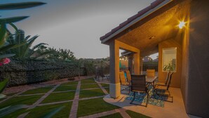 A covered outdoor patio with a pool, seating area, and a view of the surrounding garden and hills. - Good Vibes off the strip, 5BR, Secret room, 2 King Beds, Pool and Spa (Henderson)