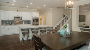 A modern kitchen with white cabinets, stainless steel appliances, and a central island with bar stools. - Good Vibes off the strip, 5BR, Secret room, 2 King Beds, Pool and Spa (Henderson)