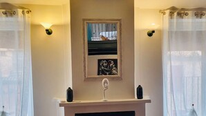 Una sala de estar con chimenea, un sofá y un espejo en la pared.