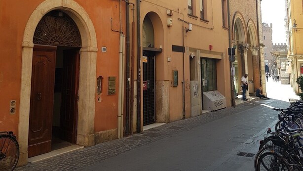 Una calle estrecha flanqueada por edificios con arcos en puertas y ventanas.
