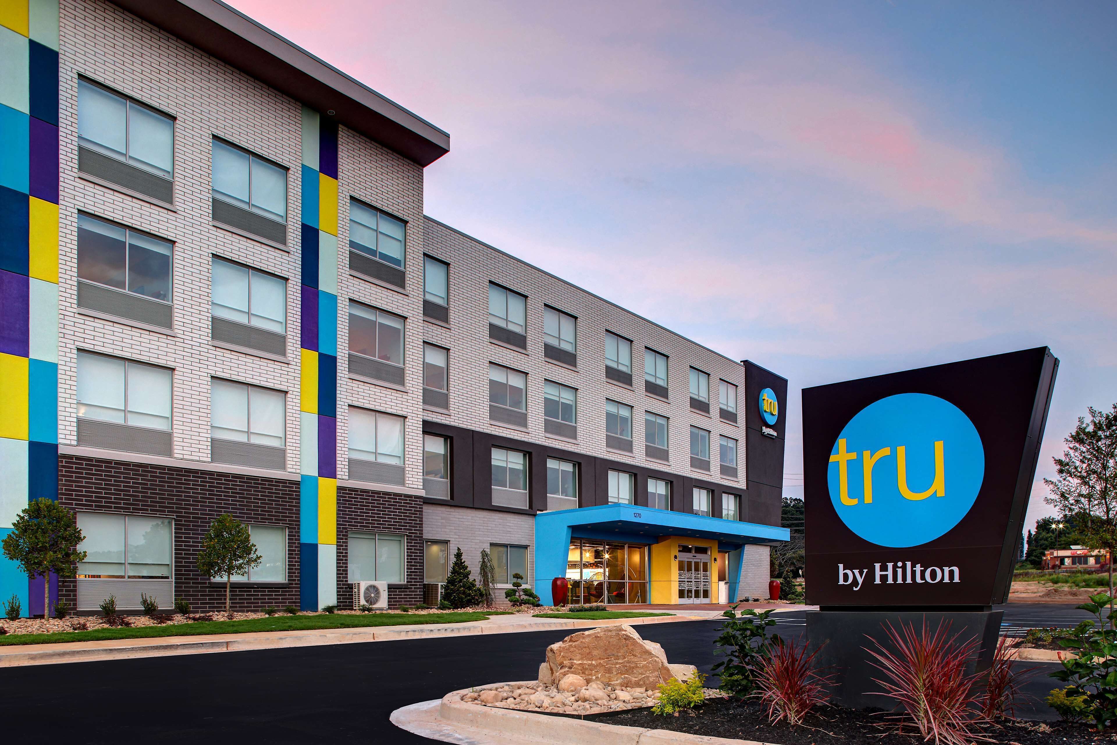 A hotel with a modern design, featuring a mix of brick and glass facade, and a prominent blue entrance sign.