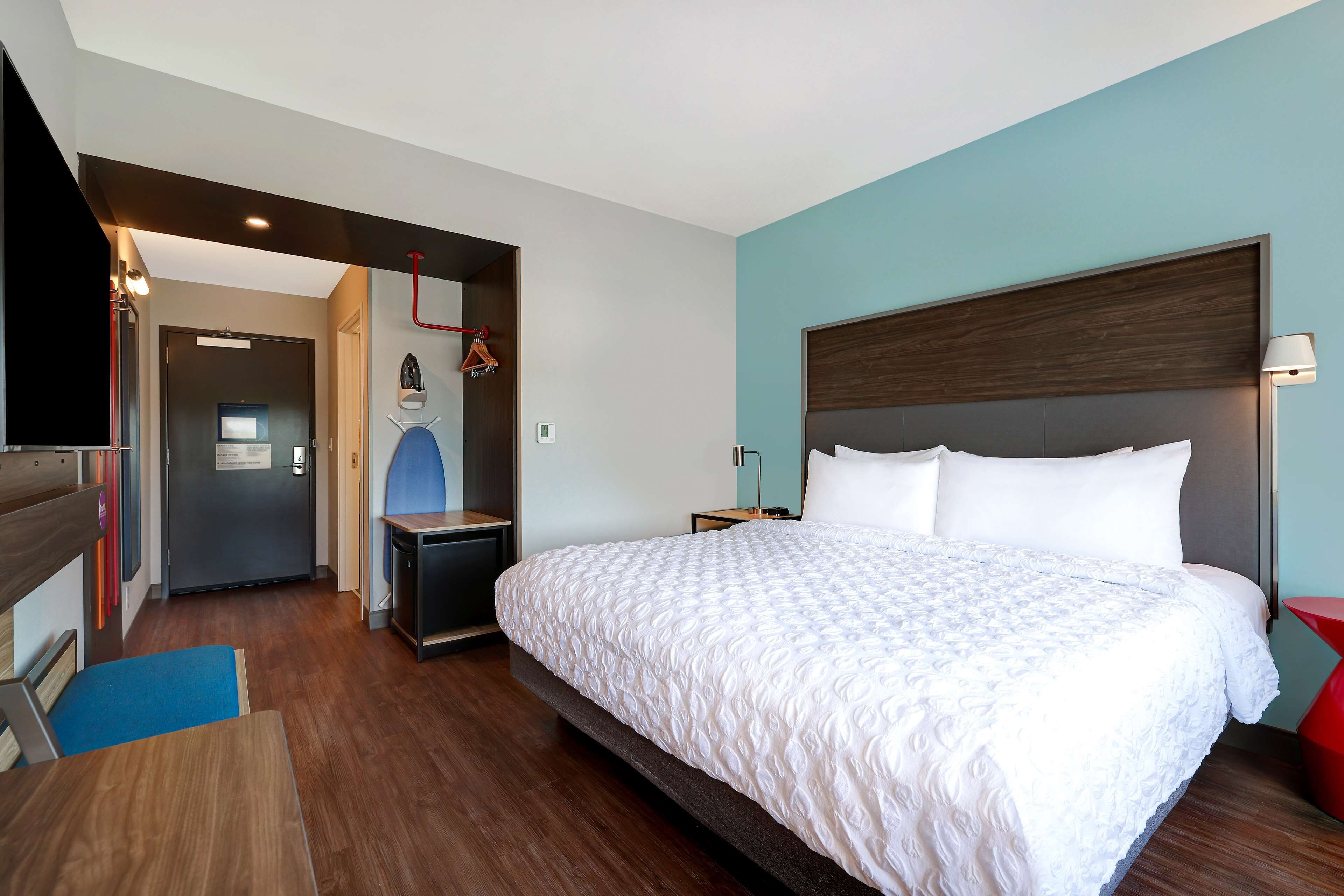 Ein Hotelzimmer mit einem großen Bett, einem Schreibtisch, einem Stuhl, einem Fernseher und einem Kleiderschrank.
