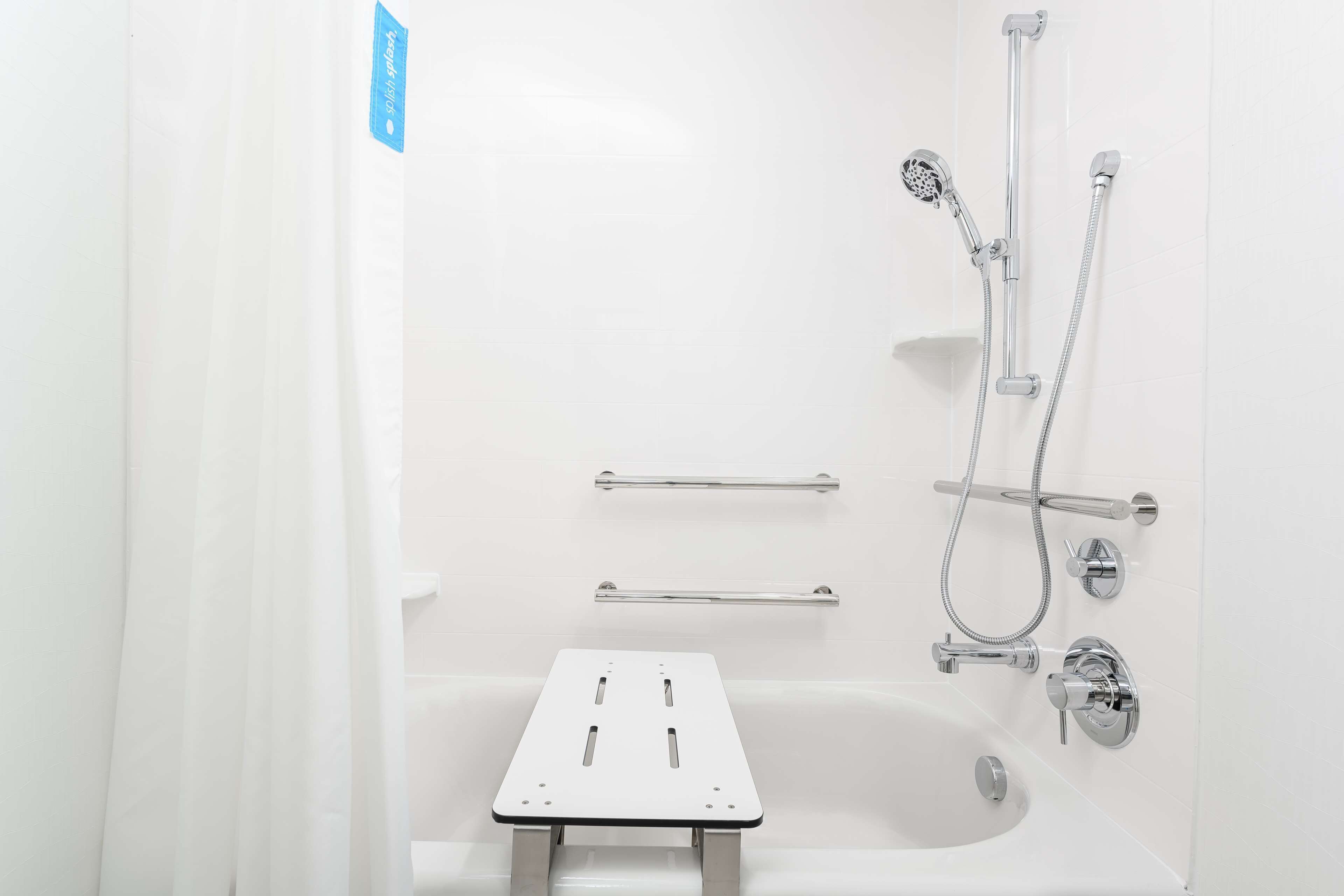 A modern bathroom with a bathtub, shower, and grab bars.