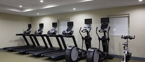 A gym with treadmills, elliptical machines, and a stationary bike.