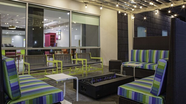 A modern outdoor seating area with wicker furniture and a fire feature. - Home2 Suites by Hilton Baton Rouge Citiplace (Baton Rouge)