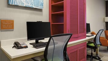 A modern office space with a desk, computer, chairs, and a phone.
