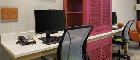 A modern office space with a desk, computer, chairs, and a phone.