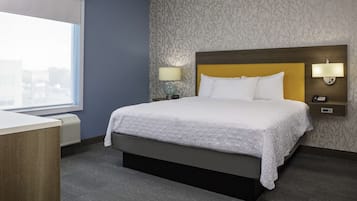 Quarto de hotel com uma cama grande, uma mesa, uma janela e parede estampada.