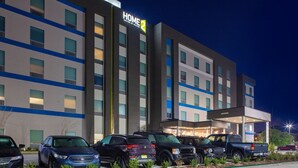 A hotel with a modern design, featuring a prominent 'HOME 2' sign, multiple parking spaces, and a covered entrance. - Home2 Suites by Hilton Baton Rouge Citiplace (Baton Rouge)
