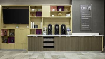 Un espace cuisine moderne doté d’un téléviseur encastré, de machines à café et d’une poubelle.