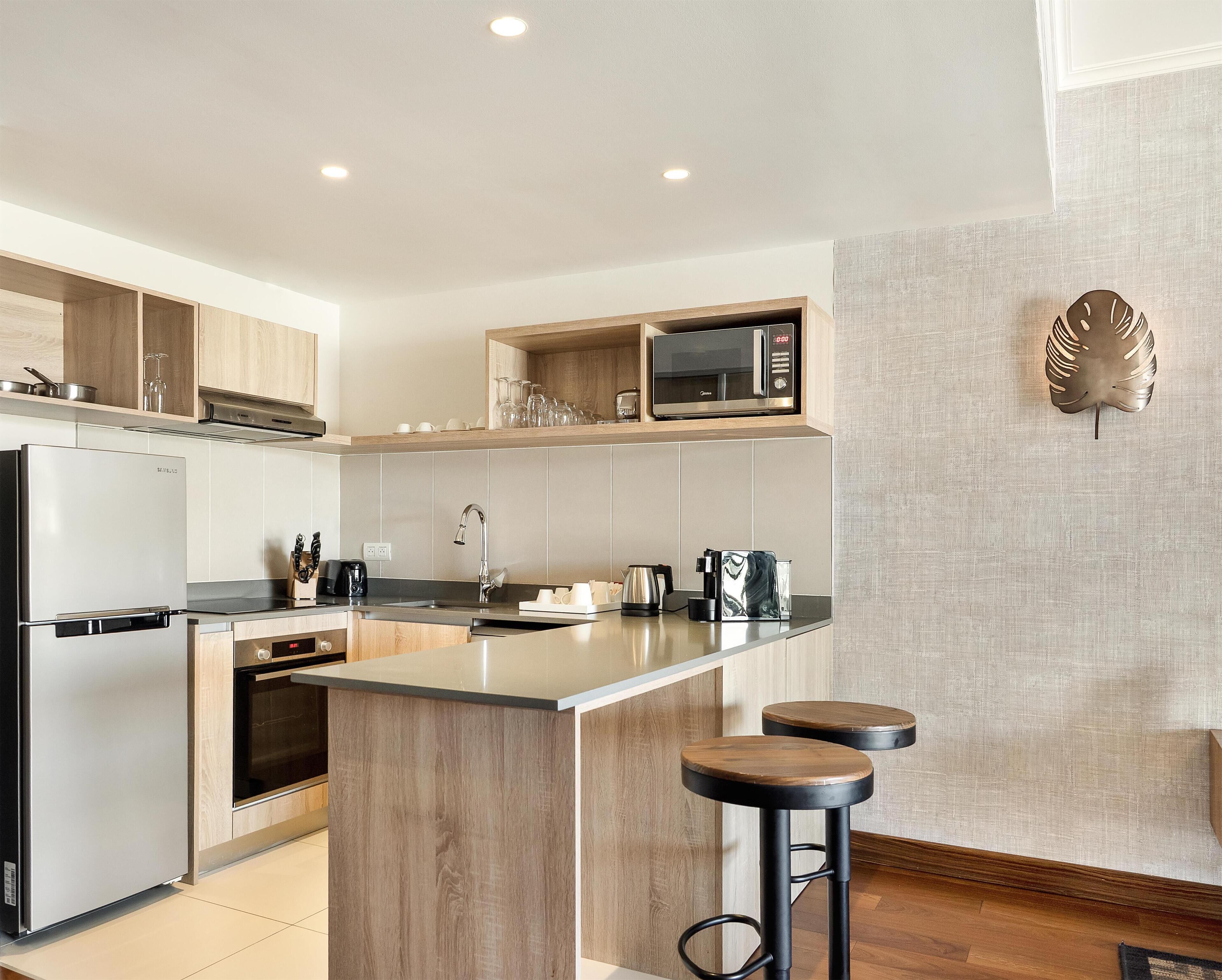 A modern kitchen with a built-in microwave, stainless steel appliances, and wooden accents.