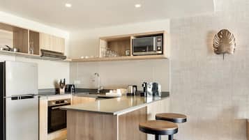 A modern kitchen with a built-in microwave, stainless steel appliances, and wooden accents.