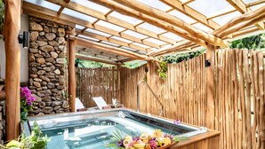 A hot tub with a wooden pergola overhead, surrounded by a stone wall and wooden fence. - Hilton Hotel Tahiti (Faaa)