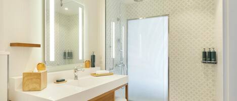 A modern bathroom with a large mirror, two sinks, a shower, and a towel rack.