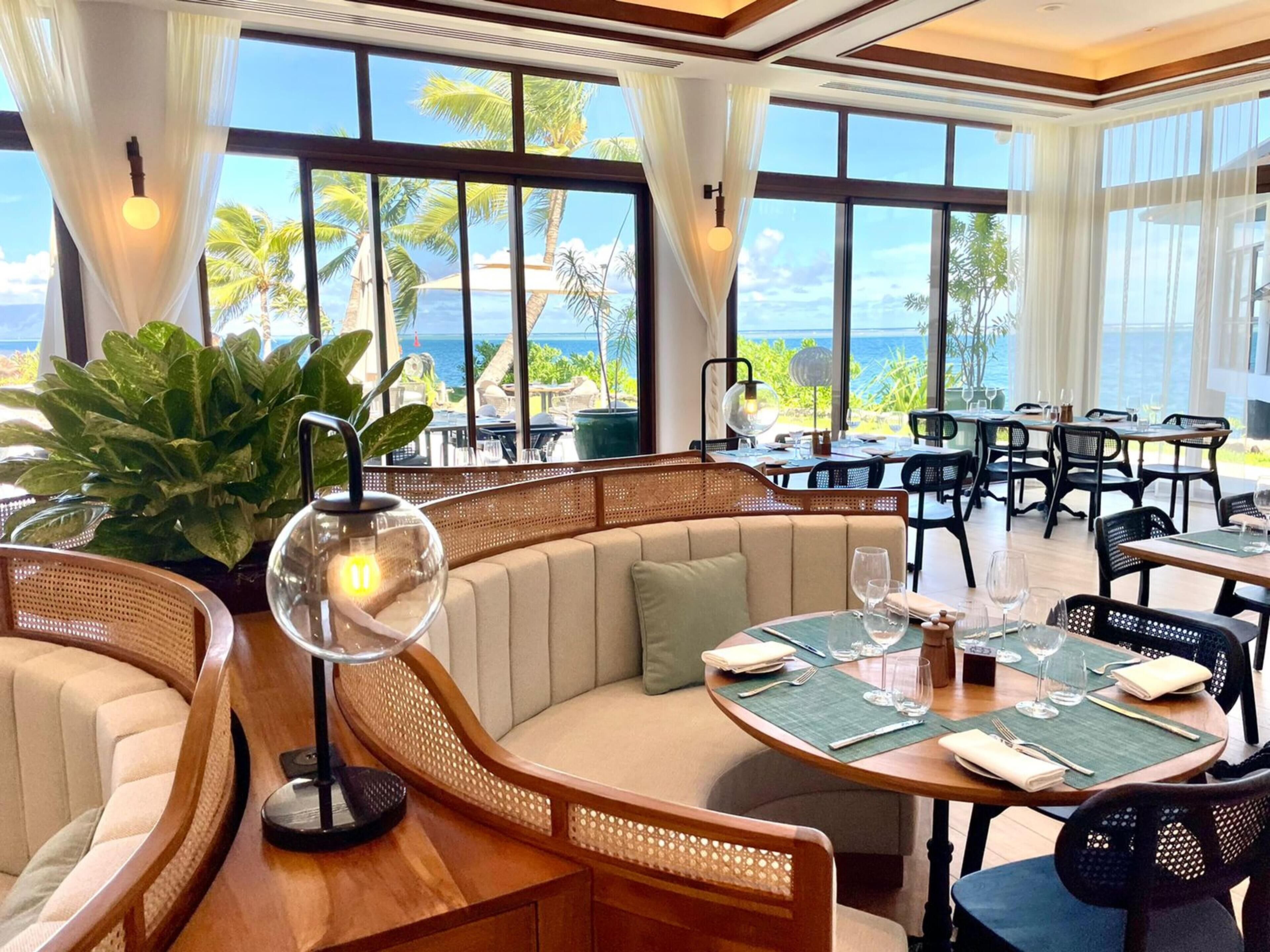 A restaurant with a view of the ocean, featuring wooden furniture and large windows.