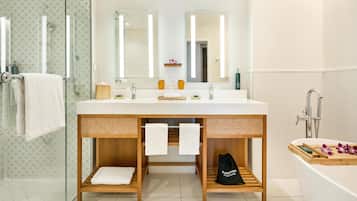 A modern bathroom with a large mirror, two sinks, a shower, and a bathtub.