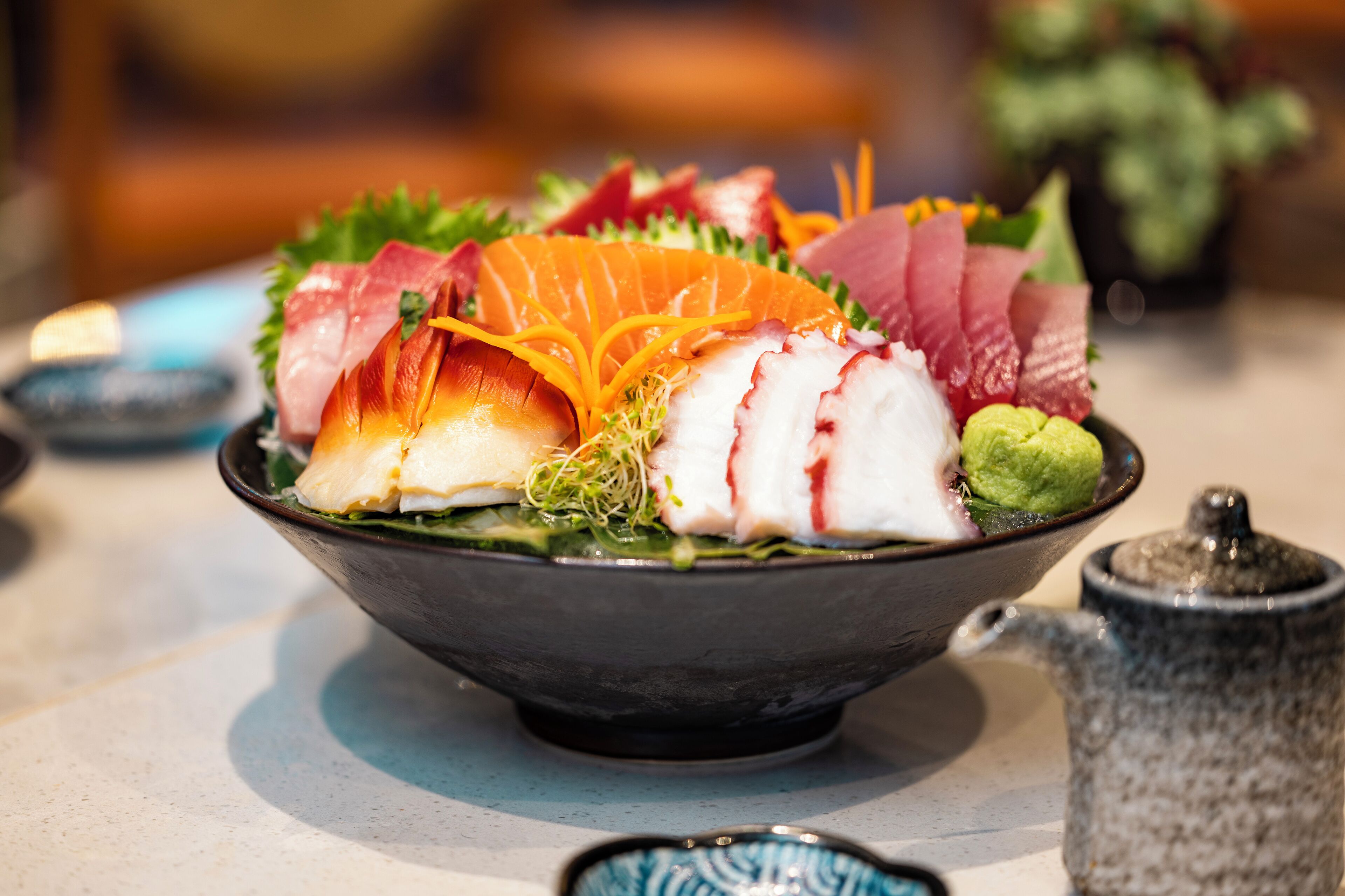 Un bol de sashimi con diferentes tipos de pescado y guarniciones.