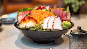 Un bol de sashimi con diferentes tipos de pescado y guarniciones.