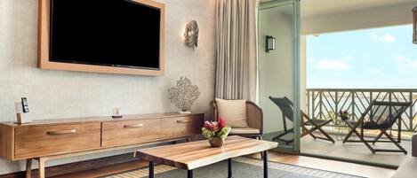 Una sala de estar moderna con televisión de pantalla plana, muebles de madera, un banco y vista al mar.