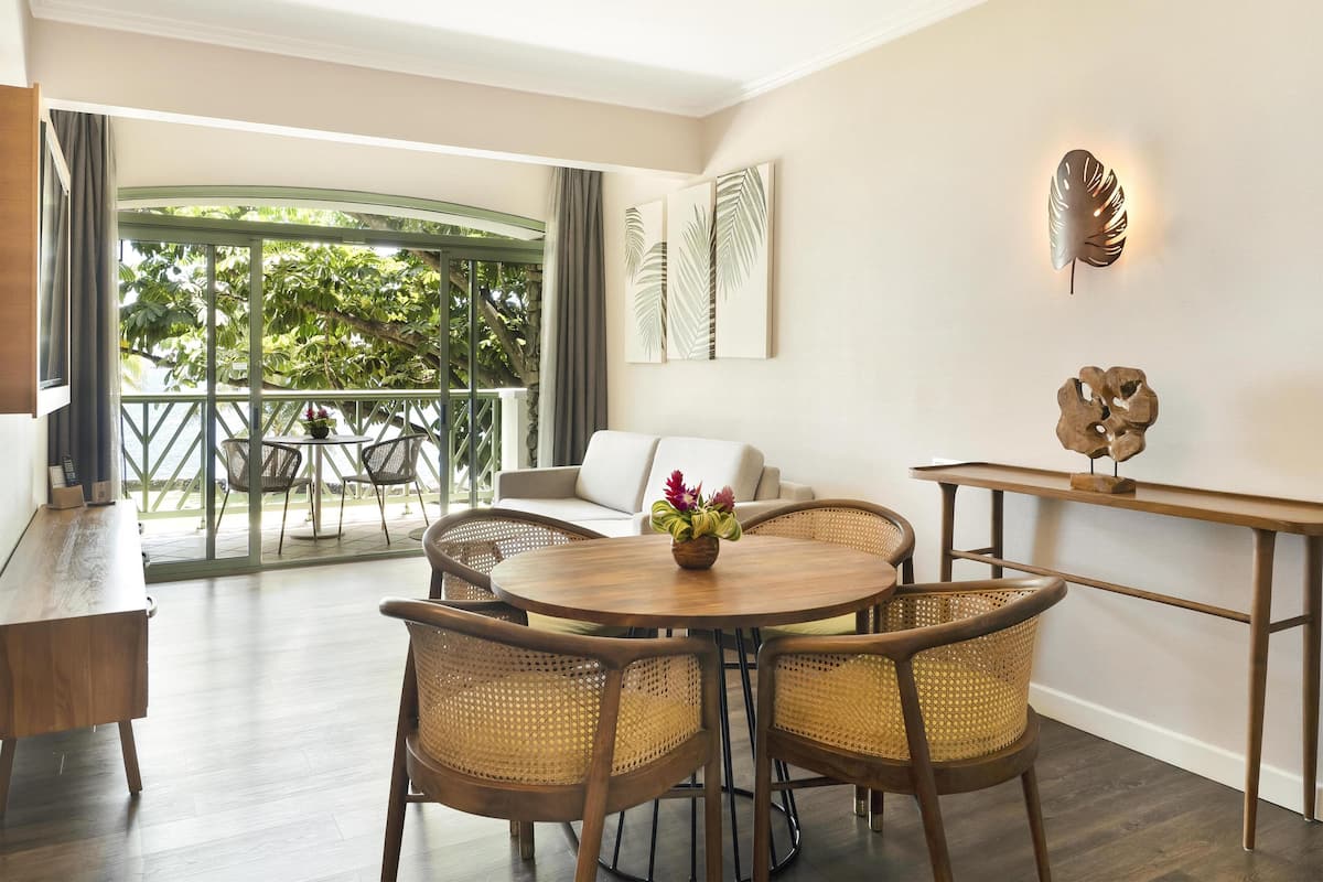 A modern room with a dining area, a sofa, and a view of greenery outside.