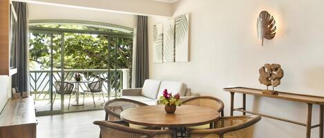 A modern room with a dining area, a sofa, and a view of greenery outside.
