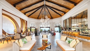 A spacious lobby with a high ceiling, a central seating area, a bar, and large windows offering views.