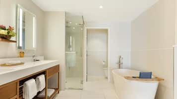 Un baño moderno con una bañera grande, una ducha con cerramiento de vidrio y un tocador con espejo.