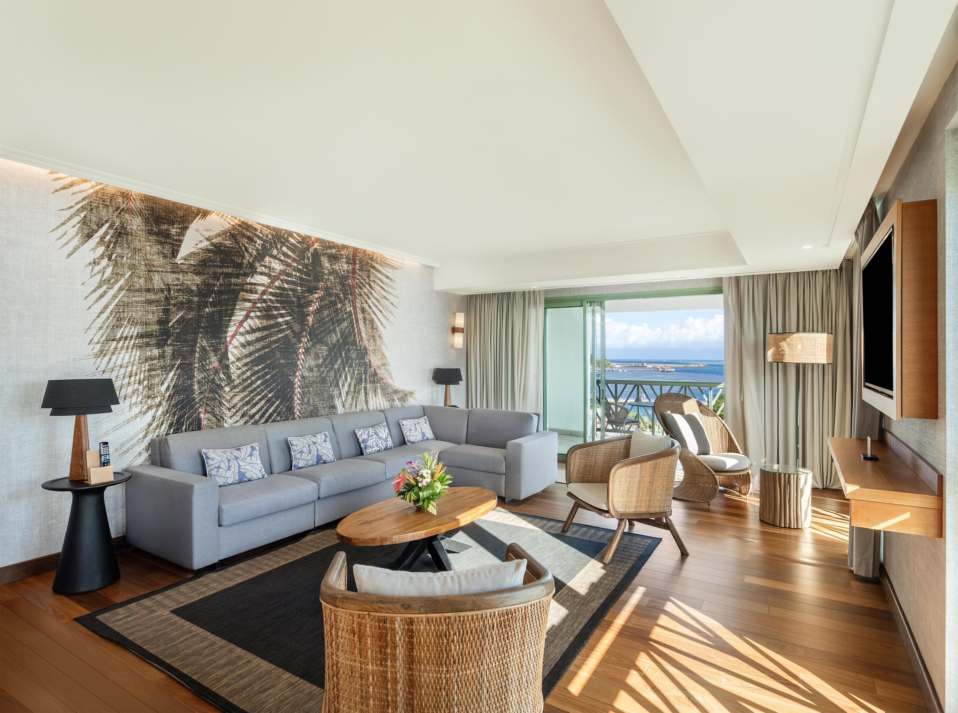 Ein modernes Wohnzimmer mit einer Couch, Sesseln, einem Couchtisch und einer großen Wandmalerei.
