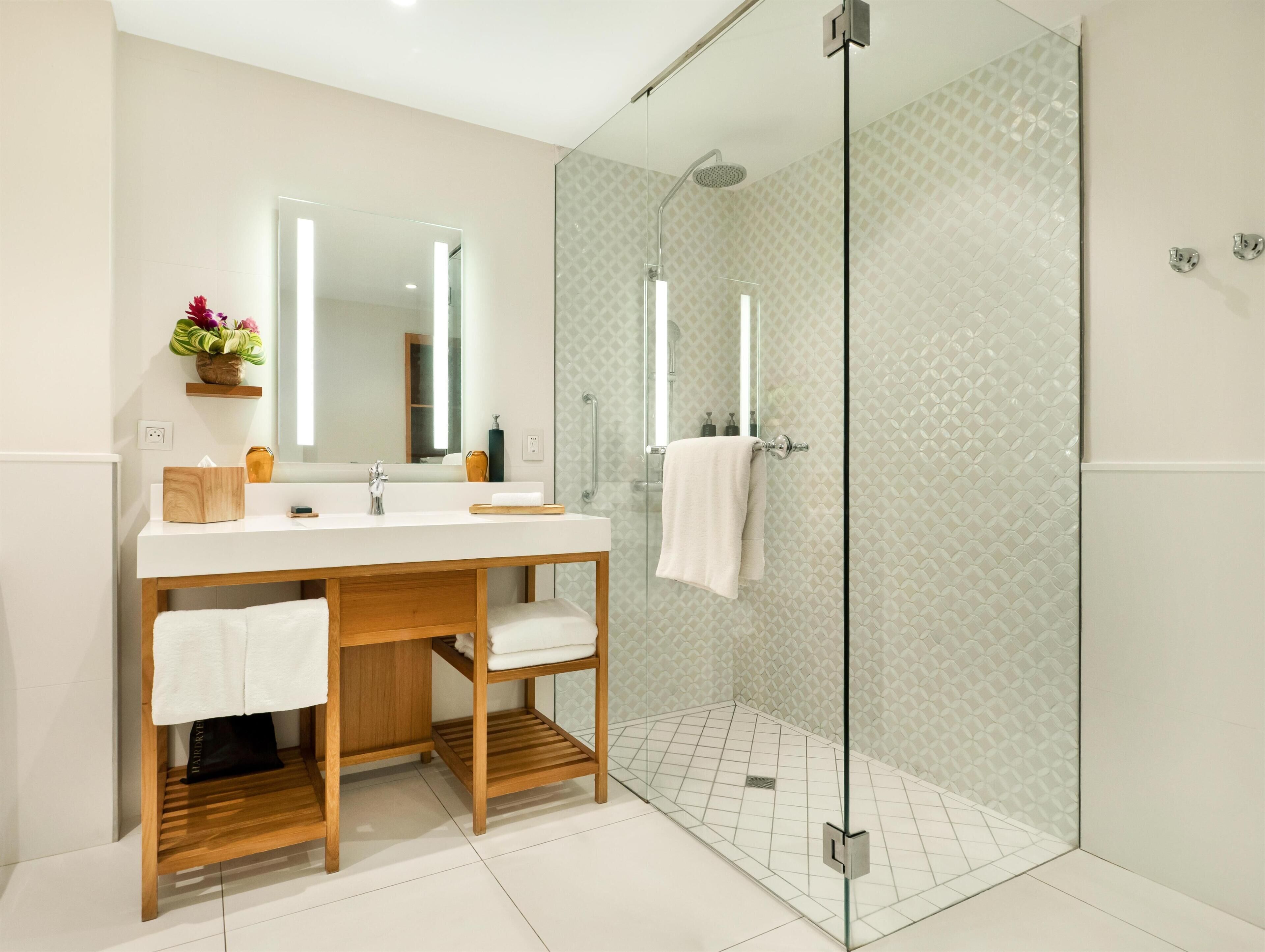 Un baño moderno con cabina de ducha de vidrio, tocador de madera y un espejo grande.