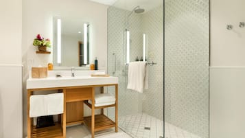 Un baño moderno con cabina de ducha de vidrio, tocador de madera y un espejo grande.