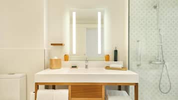 A modern bathroom with a large mirror, a wooden vanity, a shower, and a toilet.